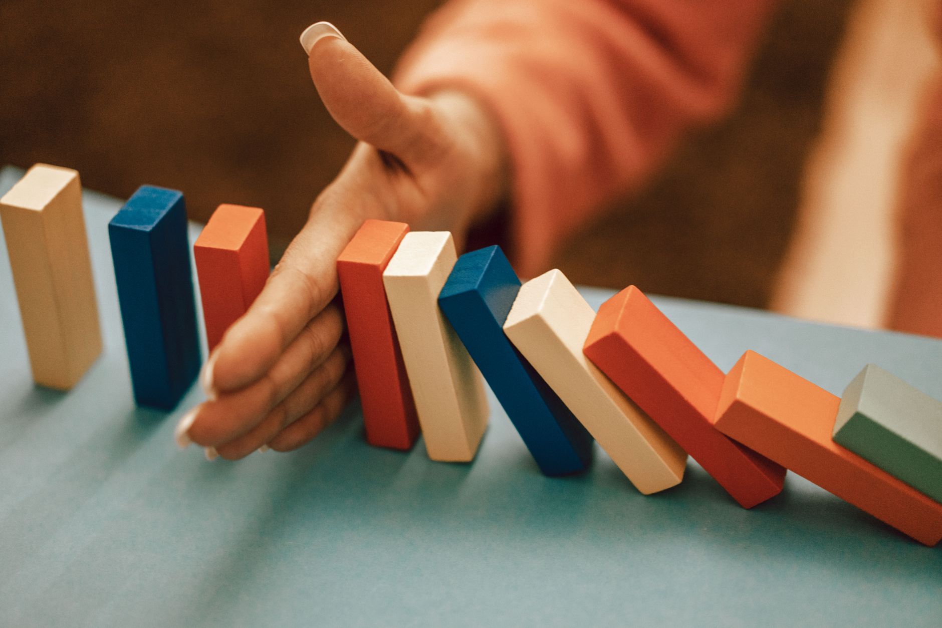 A hand stopping a line of falling dominoes