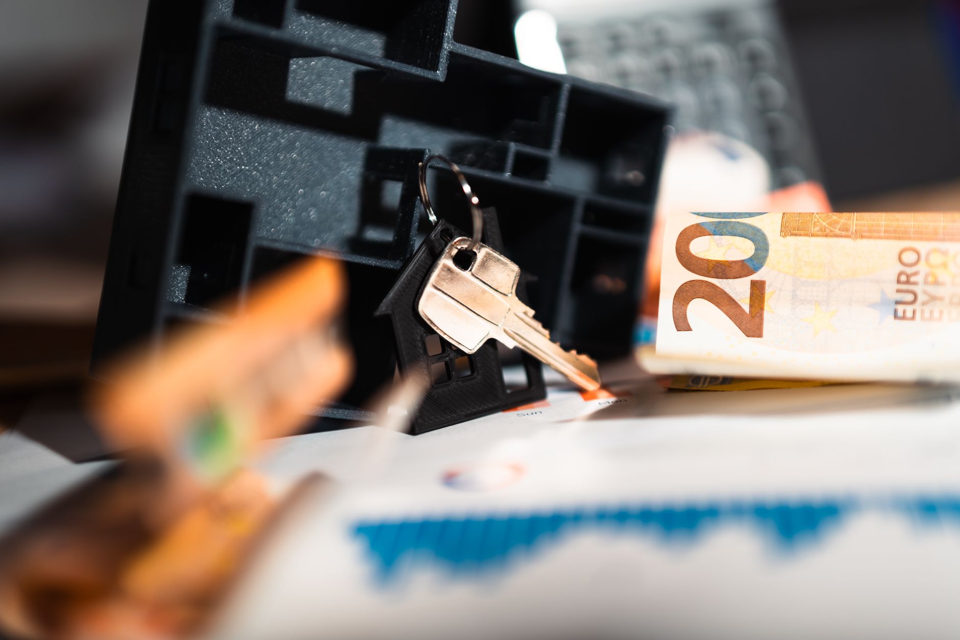 House keys resting on a desk beside banknotes