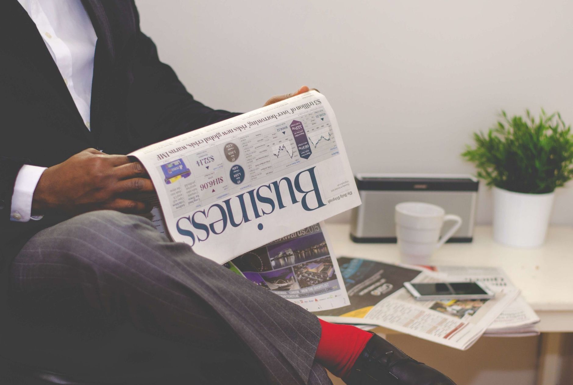 A person reading the business section of a newspaper at a desk