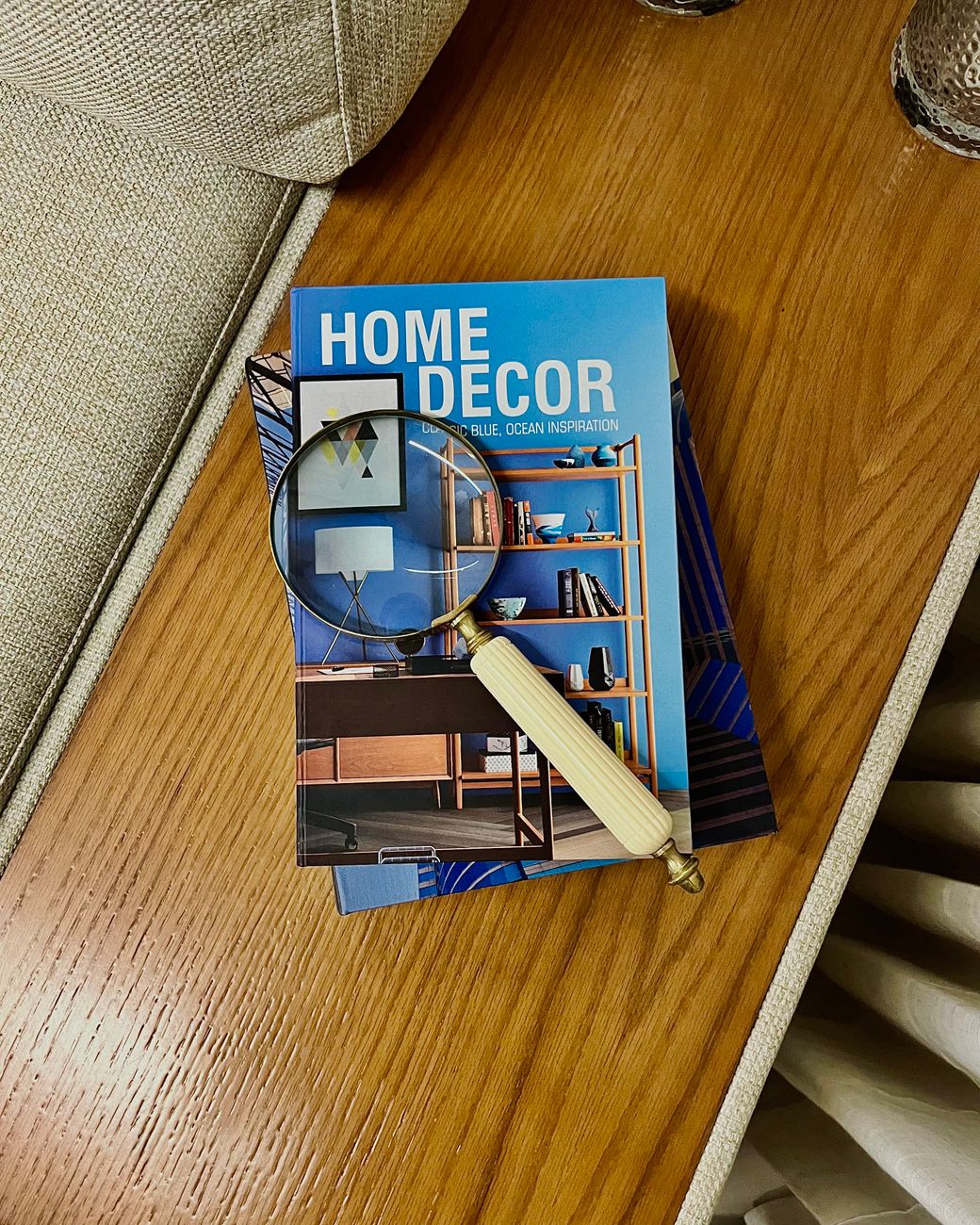 A home decor magazine and magnifying glass on a table